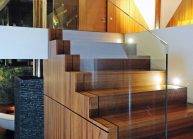 Venkovský rodinný dům od architekta Radomíra Grafka – detail dřevěného schodiště se skleněným zábradlím.